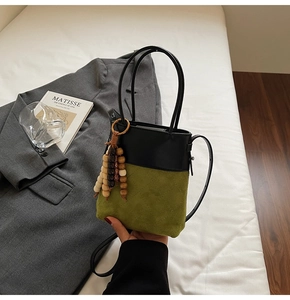 Detail of green quilted suede bucket bag with color-block leather and wooden bead tassel