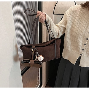 Détail du sac bandoulière en cuir dépoli marron foncé avec breloques de baseball