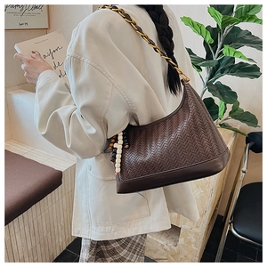 Detail of dark brown woven hobo bag with gold chain strap and bead tassel decoration