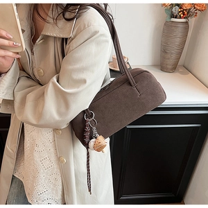 Detail der dunkelbraunen Retro-Schultertasche mit Wildledertextur und Baseball-Anhängern