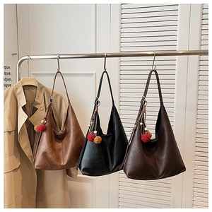 Three large tote bags in brown and black leather with plush charms on a metal hanger