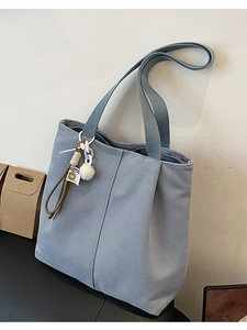 Grey-blue canvas tote bag for women with large capacity and decorative charms on dark surface