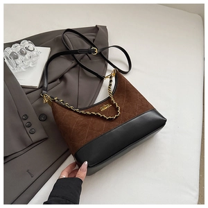 Detail of quilted suede dumpling bag with gold chain and metal lock on soft background