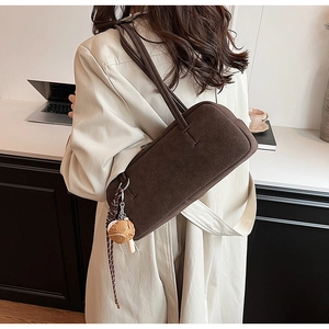 Detail einer Vintage-Schultertasche aus braunem Wildleder mit süßem Burger-Anhänger am Set