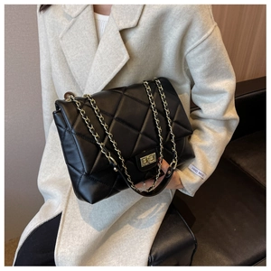Close-up of black quilted shoulder bag with gold metal twist lock and leather chain strap