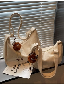 Set of cream crescent shoulder bags with plush monster charm and pleated leather texture