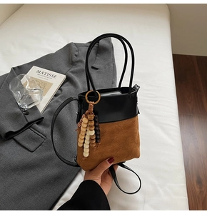 Detail of contrasting black leather and brown suede bucket bag with beaded charm