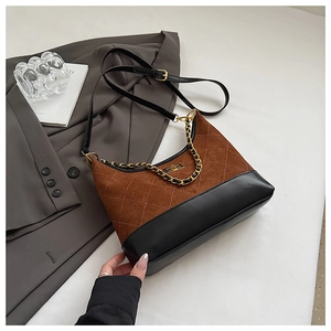 Detail of rhombic quilted bag with gold twist lock and metallic chain on grey fabric