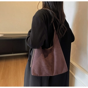 Detailed view of large dark reddish-brown suede tote bag worn by a model