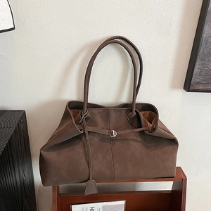 Detail of dark brown matte suede tote bag with metal D-ring and elegant leather charm