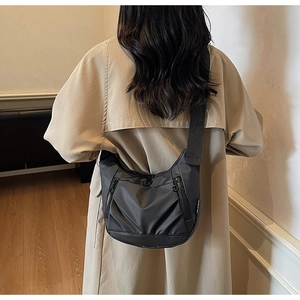 Detailed view of black crescent oxford bag worn by model in stylish trench coat