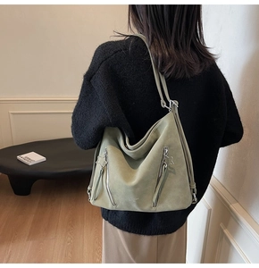 Detail of light green suede tote bag with star-shaped zippers and brand lettering