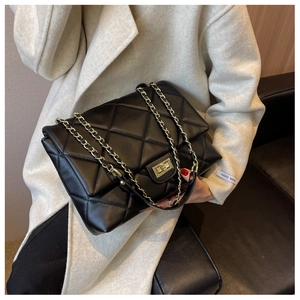 Detail of black quilted leather crossbody bag with gold turn-lock and chain strap