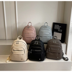 Litchi texture fashion backpacks in five colors displayed on white tiered pedestals