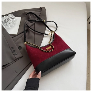 Detail of red quilted suede and black leather bag with gold chain and metal lock