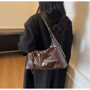 Détail d'un sac hobo en cuir marron poli avec poche zippée et détail de nœud tressé