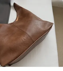 Close-up of brown distressed leather texture and fine stitching on large tote bag