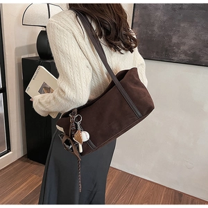 Détail du sac bandoulière en daim marron foncé avec un pendentif gant de baseball