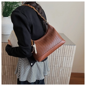 Detail of brown herringbone woven suede bag with chain strap and beaded pendant