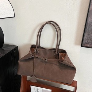 Macro shot of large brown matte tote bag with metallic ring and long straps on wood