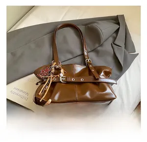 Détail d'un sac à bandoulière en cuir brillant marron avec sangle à boucle et breloque léopard