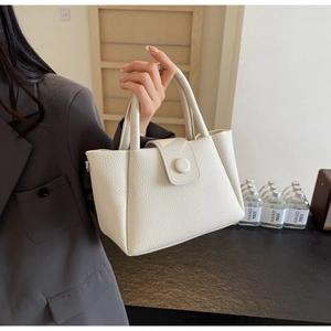 Detail of the cream textured faux leather and structural handle of the bucket bag