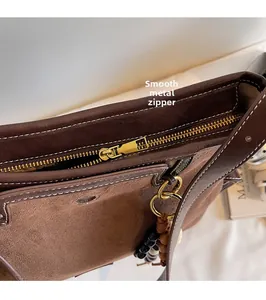Detail of golden metal zipper and beaded pendant on brown suede patchwork handbag