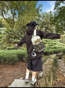 Sac à dos de randonnée beige et vert armée sur un modèle dans une scène de forêt