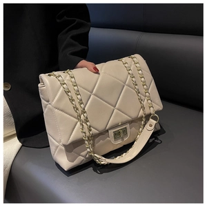 Close-up of cream quilted shoulder bag featuring gold chain strap and metal twist lock