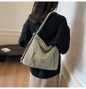 Detail of olive green tote bag featuring star-shaped zippers and suede texture