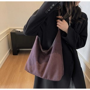 Macro detail of high-capacity dark purple suede tote bag worn on shoulder