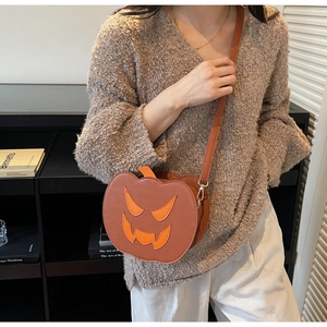 Detail of Halloween pumpkin crossbody bag with orange face patch and gold hardware