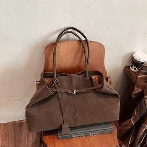 Detail of a large brown matte tote bag featuring a silver metal ring buckle and hangtag