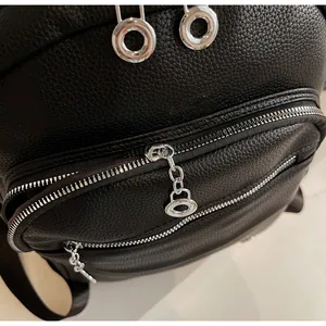 Close-up of smooth silver zipper and metal chain pull on black lychee grain backpack