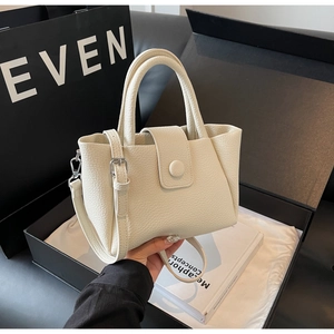 Detail of off-white lychee grain leather bucket bag with top handle and shoulder strap