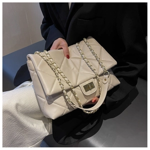 Detail of quilted beige crossbody bag featuring gold chain strap and metallic buckle