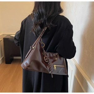 Détail du sac à bandoulière en cuir verni marron foncé avec finition brillante et métal