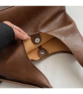 Detail view of the magnetic buckle closure on a brown PU leather bucket shoulder bag
