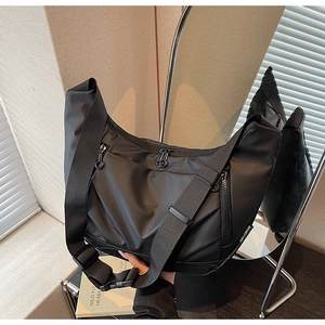 Macro detail of black oxford crossbody bag with multiple zippers and wide strap