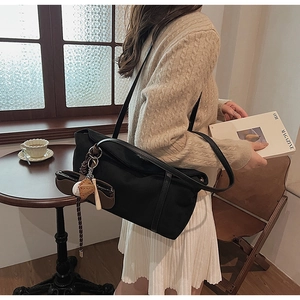 Detail view of large black retro matte shoulder bag with baseball charms on a wooden table