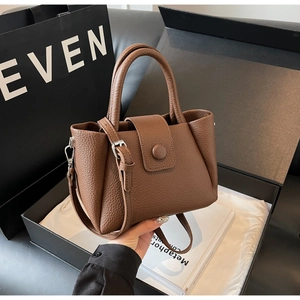 Close-up of dark brown lychee grain leather handbag with detachable strap and metal clasp