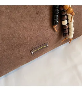 Detail of dark brown suede tote with wood bead charm and fashion label branding