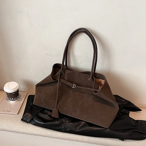 Detail of a large dark brown matte suede tote bag with decorative metal ring buckle