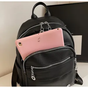 Detail view of black lychee texture backpack with silver chains and front tablet pocket