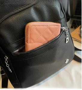 Close-up of front zipper pocket on black litchi leather backpack showing large capacity
