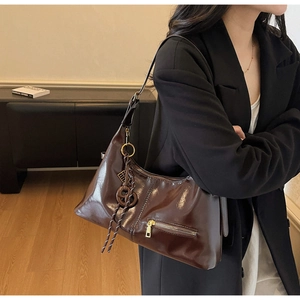 Détail du sac à bandoulière en cuir brillant marron foncé avec fermeture éclair