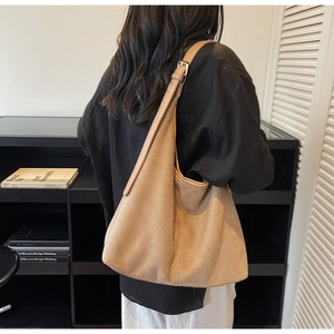 Close-up of camel suede hobo bag with adjustable leather strap and golden metal hardware
