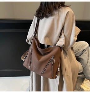 Detail of dark brown leather tote showing dual zipper pockets and star charm pendant