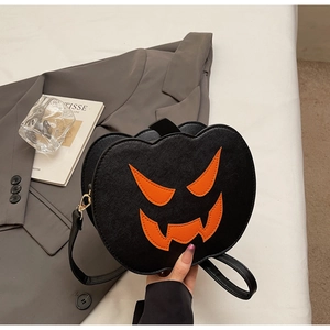 Detail of a black Halloween pumpkin crossbody bag with orange jack-o-lantern face and gold hooks