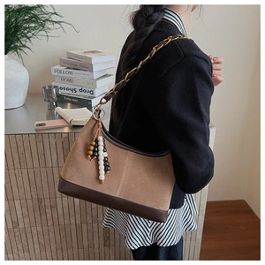Detail of vintage suede hobo bag with leather patchwork and beaded tassel charm